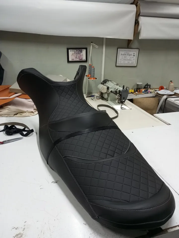 Atölye tezgâhında siyah döşemeli, şekillendirilmiş jet ski koltuğu