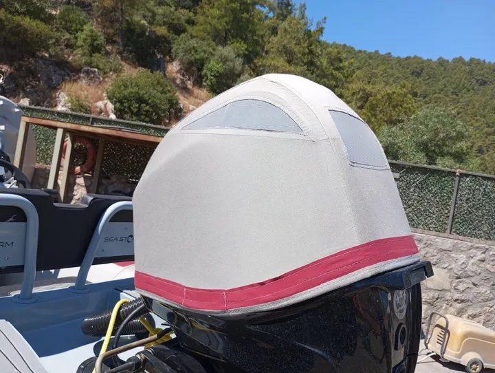 Dıştan takma motorun üst bölümüne uyarlanan açık renk kumaş kılıf ve kırmızı kenar şeridi