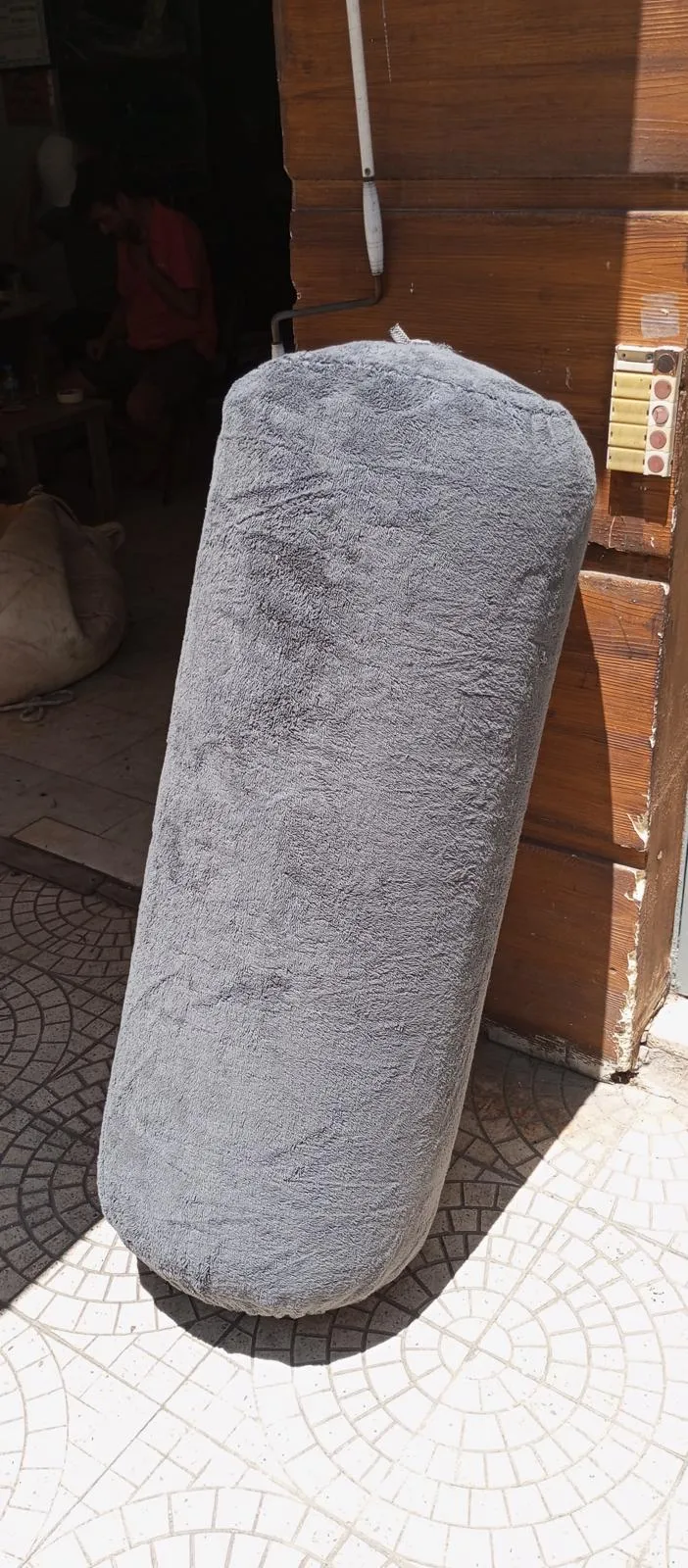 Atölyede dik duran uzun usturmaçaya giydirilmiş açık gri kumaş kılıf